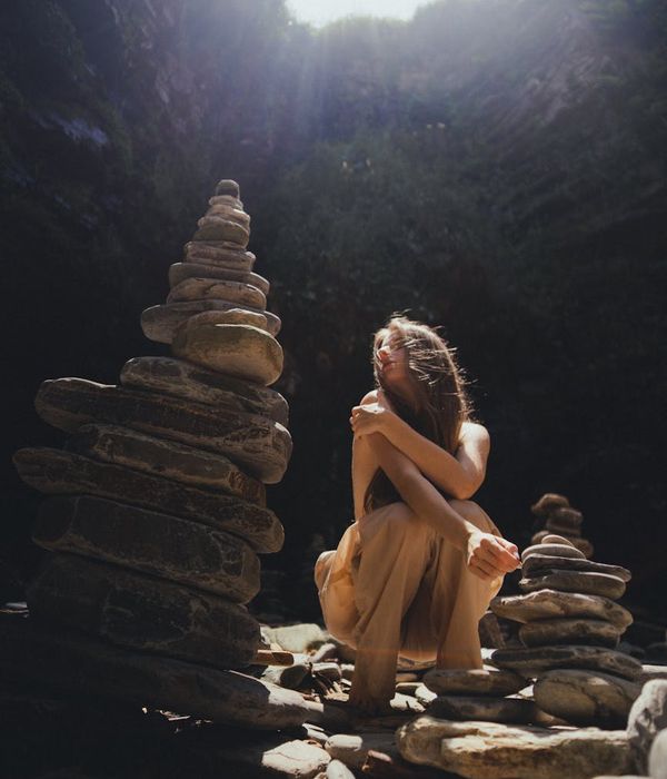 Woman in a calm yoga pose, surrounded by a serene, dark environment with cyan light trails.